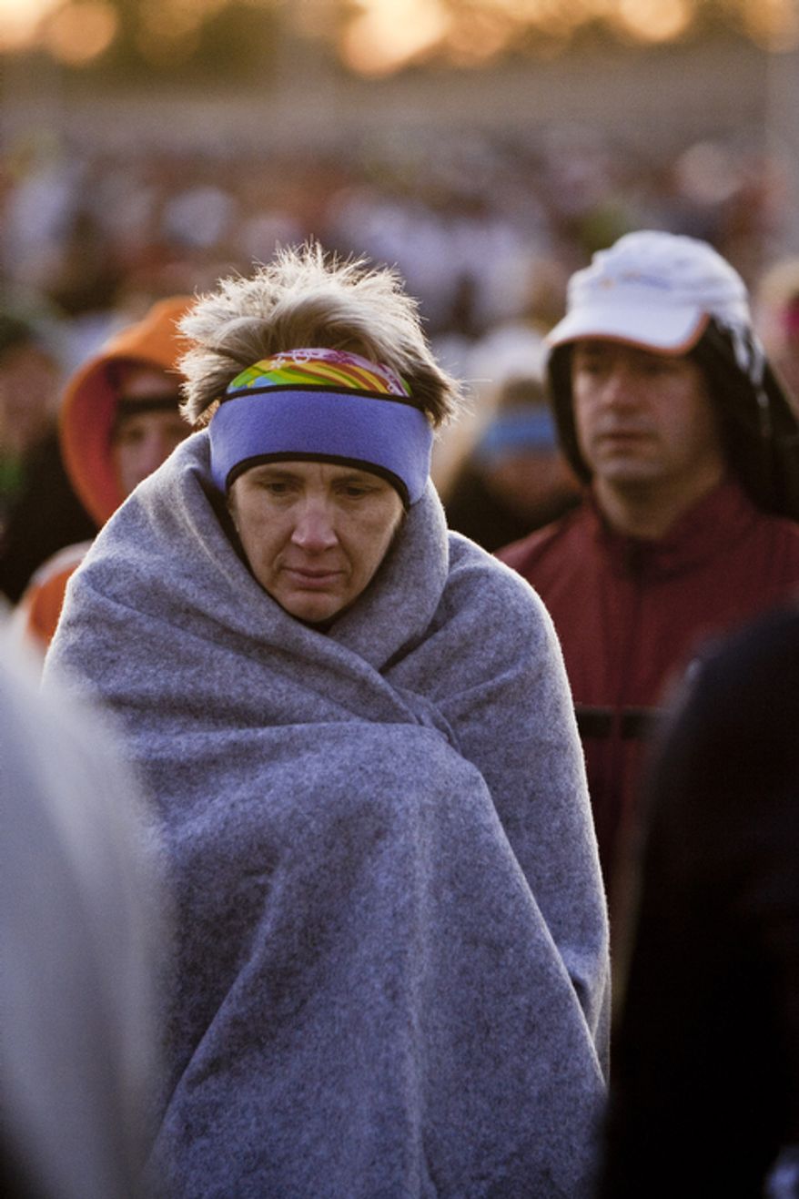 Sarah Abby, of Charlotte, N.C., keeps a blanket wrapped tightly around her as she makes her way to the start in her first Marine Corps Marathon in Arlington, Va. on Oct. 30, 2011.
(T.J. Kirkpatrick/ The Washington Times)