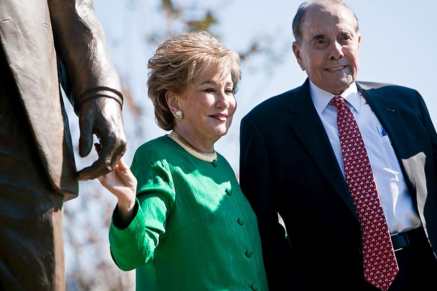 Former Transportation Secretary Elizabeth Dole and her husband, former Sen. Bob Dole, stand beside a bronze statue of Ronald Reagan at Reagan National Airport in Arlington, Va., on Nov. 1, 2011. The statue was unveiled as part of a dedication ceremony on the centennial of the former president's birth. (T.J. Kirkpatrick/The Washington Times)