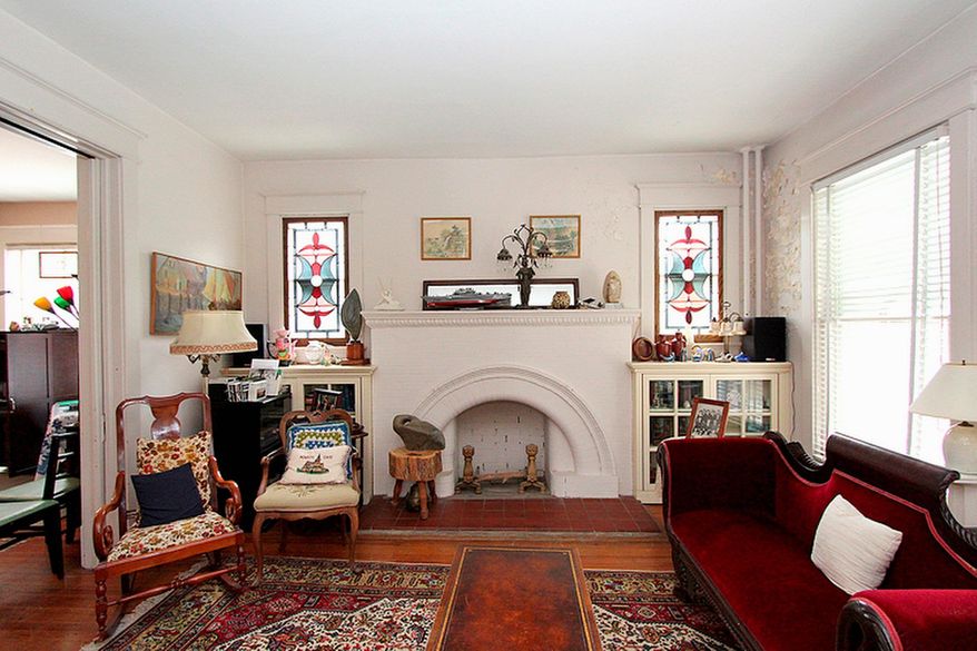 The living room's wood-burning fireplace is flanked by glass-front cabinets and stained-glass windows.