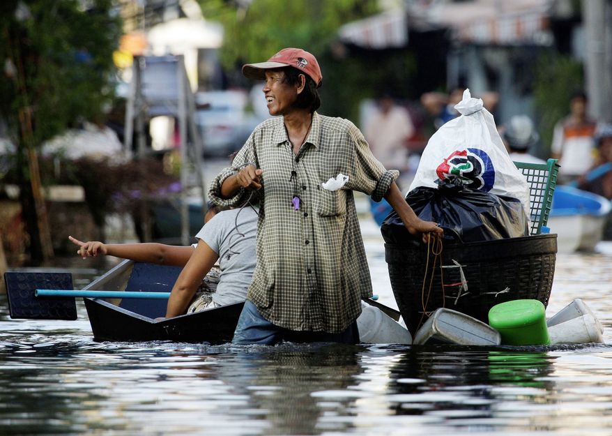 A Thai man uses an improvised float to move his goods along a flooded street in Bangkok. Rancid brown water has seeped south across the city at a rate of about a mile per day. Government officials have issued warnings to waders. (Associated Press)