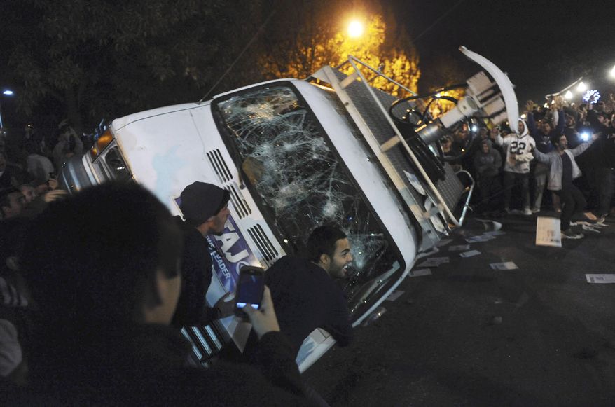 Penn State students flip a television news van during a riot after the announcement that Joe Paterno had been fired as head football coach on Wednesday, Nov. 9, 2011. (AP Photo/Pittsburgh Post-Gazette, Michael Henninger)