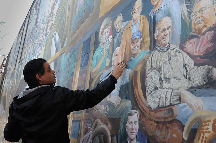 ** FILE ** Michael Pilato paints over the image of Jerry Sandusky, a former defensive coordinator at Penn State, on a mural on College Avenue in State College, Pa., on Wednesday, Nov. 9, 2011. (AP Photo/Pittsburgh Post-Gazette, Lake Fong)
