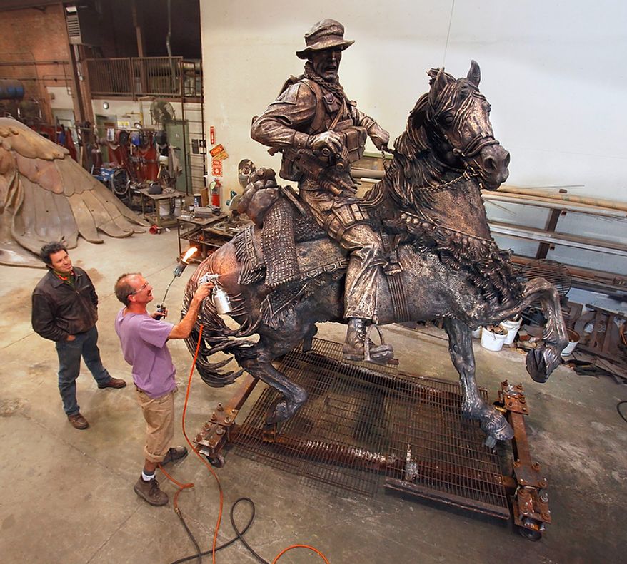 In a Friday, Nov. 4, 2011, photo, Douwe Blumberg, left, watches as Todd Jenkins puts a patina on Blumberg's statue honoring U.S. Special Forces serving in Afghanistan, in Norman, Okla. It was expected to be unveiled on Veteran's Day near the World Trade Center site in New York. (AP Photo/The Oklahoman, Steve Sisney)