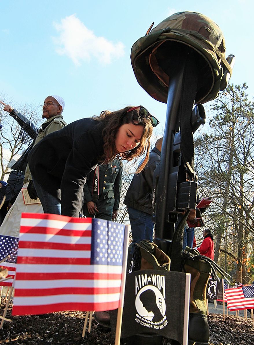 Taylor Norton places a U.S. flag in front of the Vietnam Veteran's memorial following a Veteran's Day ceremony, Friday, Nov. 11, 2011, in Eden Park in Cincinnati. (AP Photo/Al Behrman)