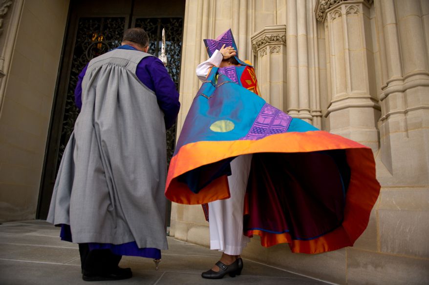 A wind gust blows the robe of the Reverend Dr. Mariann Edgar Buddle as she stands outside with Verger Duke DuTeil before she is consecrated as the ninth bishop of Washington at the service of Holy Eucharist on Sunday, November 13, 2011. (Andrew Harnik / The Washington Times)