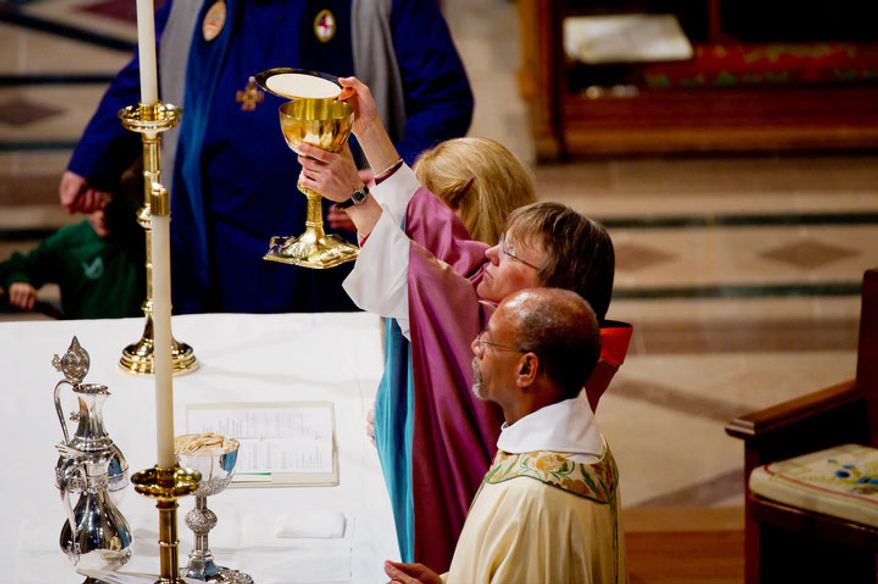 The Reverend Dr. Mariann Edgar Buddle prepares communion after being seated as the ninth bishop of Washington. (Andrew Harnik / The Washington Times)