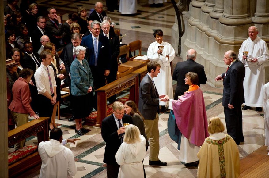 A visitor receives communion from The Reverend Dr. Mariann Edgar Buddle, right, after she is seated as the ninth bishop of Washington at the service of Holy Eucharist. (Andrew Harnik / The Washington Times)