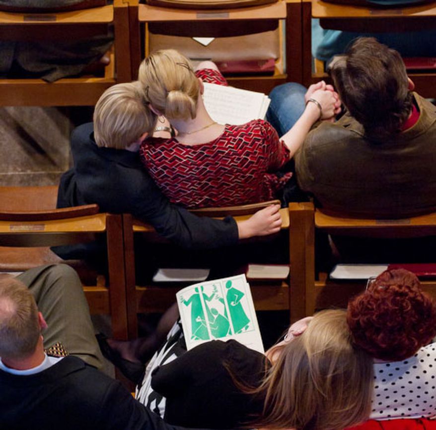 Members of the National Cathedral congregation embrace during the service of Holy Eucharist, the first day the National Cathedral. (Andrew Harnik / The Washington Times)