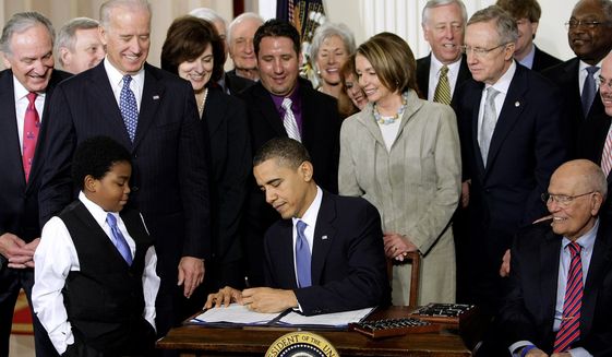 ** FILE ** President Obama signs the health care bill at the White House in Washington on March 23, 2010, flanked by smiling supporters from the House and Senate as well as Victoria Reggie Kennedy (behind Mr. Obama&#39;s right shoulder), widow of Sen. Edward M. Kennedy, who was a champion of the legislation. (Associated Press)