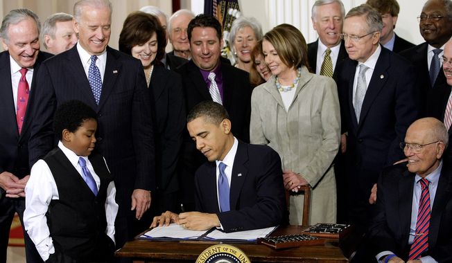 ** FILE ** President Obama signs the health care bill at the White House in Washington on March 23, 2010, flanked by smiling supporters from the House and Senate as well as Victoria Reggie Kennedy (behind Mr. Obama&#x27;s right shoulder), widow of Sen. Edward M. Kennedy, who was a champion of the legislation. (Associated Press)