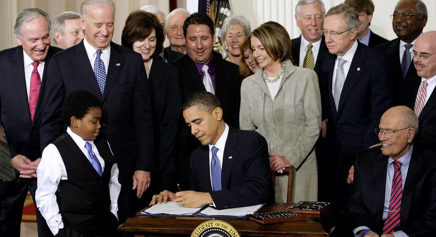 ** FILE ** President Obama signs the health care bill at the White House in Washington on March 23, 2010, flanked by smiling supporters from the House and Senate as well as Victoria Reggie Kennedy (behind Mr. Obama&#39;s right shoulder), widow of Sen. Edward M. Kennedy, who was a champion of the legislation. (Associated Press)