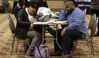 Tonya Crenshaw, left, and Kendrick Haraalson fill out applications at a job fair Wednesday, Oct. 26, 2011, in Brookpark, Ohio. The number of people seeking unemployment benefits dipped slightly last week, though not by enough to suggest that hiring is picking up. (AP Photo/Tony Dejak)