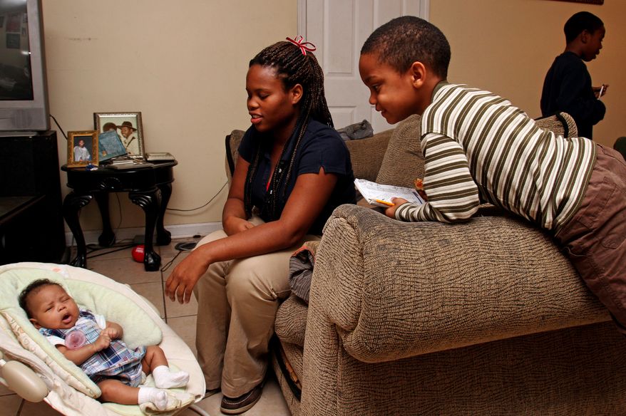 **FILE** Javonte Robinson (right), 4, looks in on his 2-month-old cousin, Bre'Azia Aaliyah Bryant, as she rests with her mother, Gautier High School student Jasmine Jones, 18, at her house in Gautier, Miss. (Associated Press/The Sun Herald)