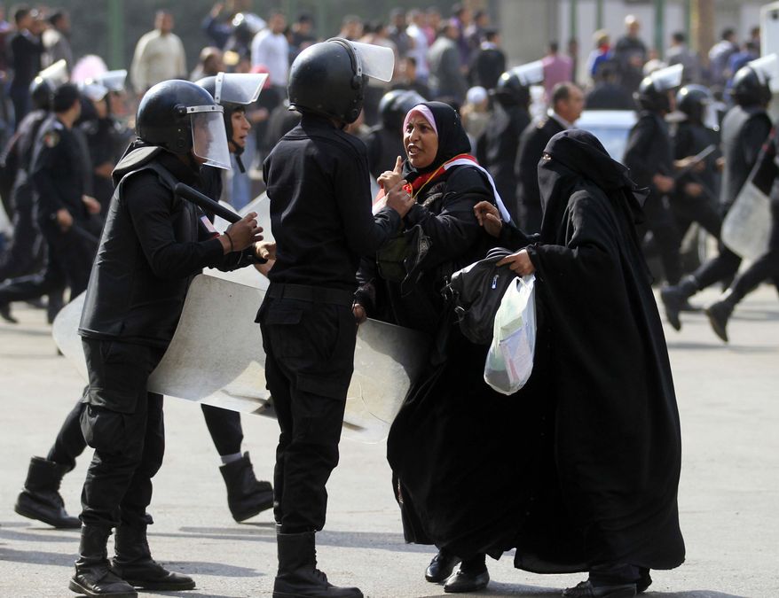 A female protester gestures as she argues with Egyptian riot police officers in Tahrir Square in Cairo, Egypt, Saturday, Nov. 19, 2011. Egyptian riot police beat protesters and dismantled a small tent city set up to commemorate revolutionary martyrs in Cairo's Tahrir Square on Saturday. (AP Photo/Khalil Hamra)