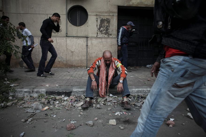 A protester overcome by tear gas rests from clashes with Egyptian police Sunday near the interior ministry in Cairo. (Associated Press)