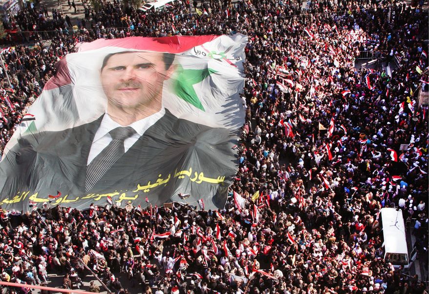 Pro-regime Syrians carry a huge portrait of President Bashar Assad during a demonstration to show their solidarity with him in Damascus on Sunday. (Associated Press)