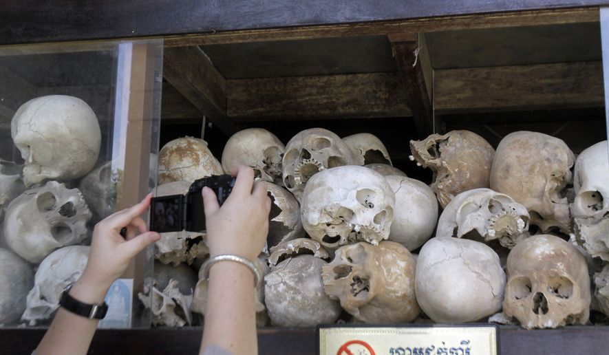 A tourist takes pictures of human skulls of Cambodian Khmer Rouge victims at Choeung Ek stupa, better known as the "Killing Fields," on the outskirts of Phnom Penh, Cambodia, Sunday, Nov. 20, 2011. (AP Photo/Heng Sinith) ** FILE **