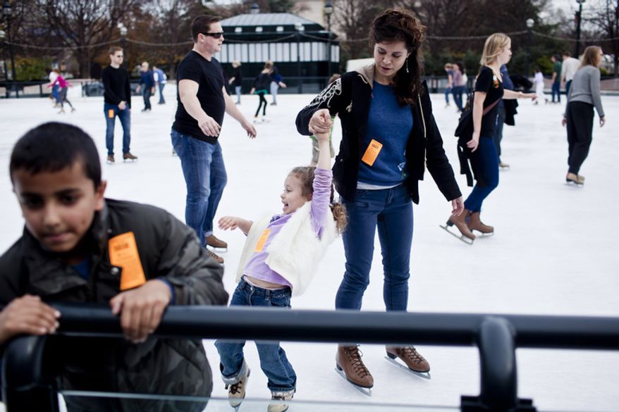 Lilla Harrigan, 5, at center, holds tight to her mother Cheyenne Bsaies, of Fairfax, Va., as they skate. (T.J. Kirkpatrick/ The Washington Times)