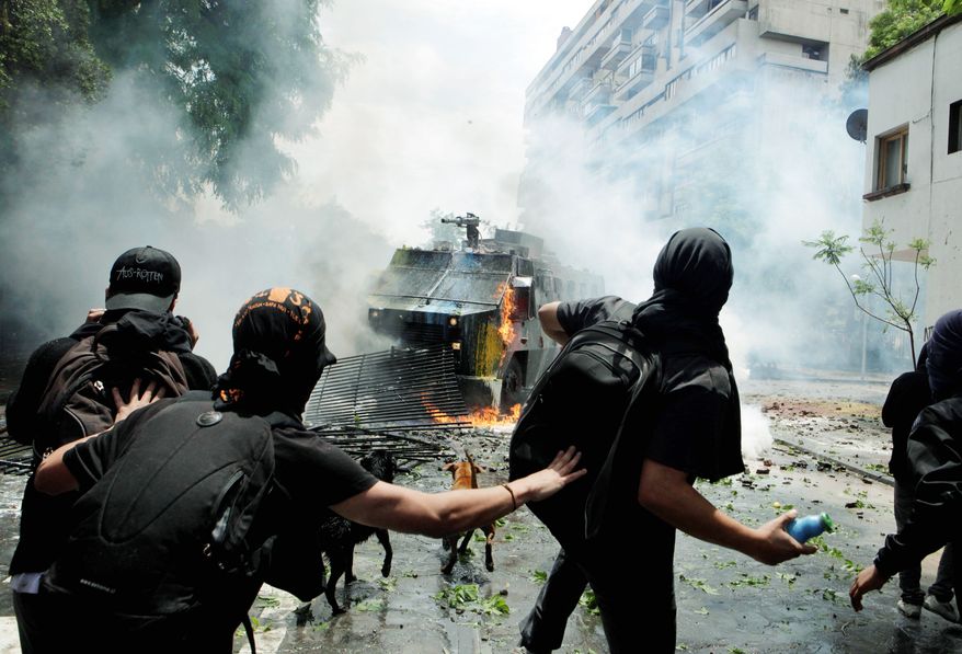 Protesters confront police in a vehicle spraying water during a protest Friday in Santiago demanding education reform.