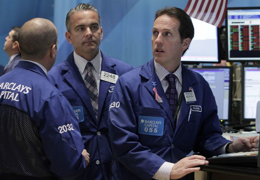 From left: Specialists James Denaro, Christopher Culhane and Glenn Carell work on the floor of the New York Stock Exchange on Nov. 21, 2011. (Associated Press)