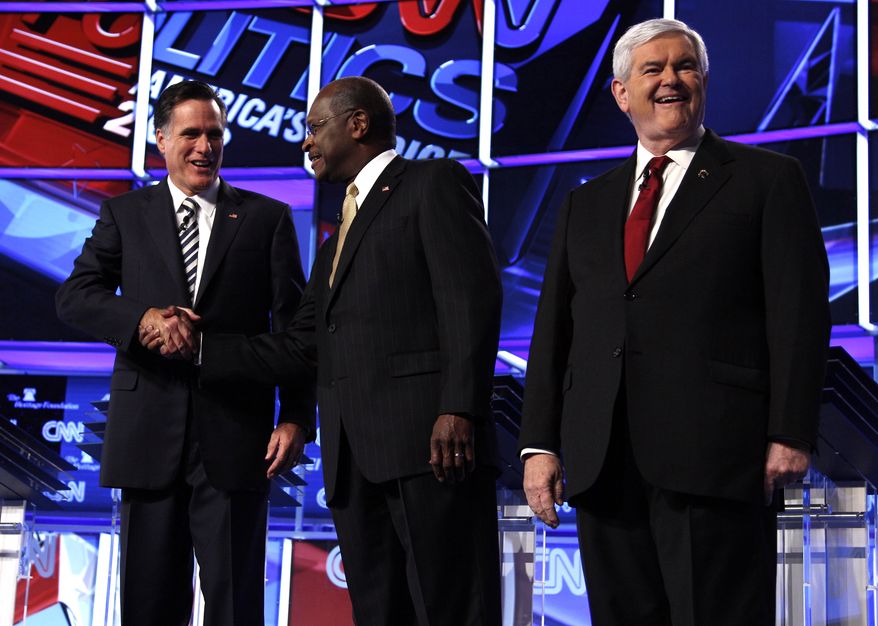 Republican presidential candidates from left, former Massachusetts Gov. Mitt Romney shakes hands with businessman Herman Cain, as former House Speaker Newt Gingrich stands on stage before a Republican presidential debate in Washington, Tuesday, Nov. 22, 2011. (AP Photo/Evan Vucci)