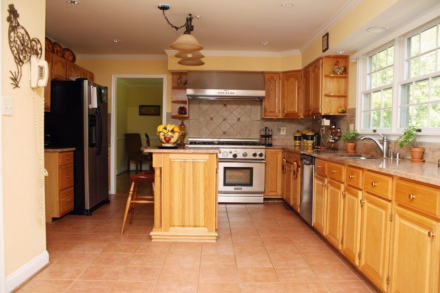 The kitchen features granite counters and a six-burner stove. It has ceramic tile floors and a center island with an overhang that can be used as a breakfast bar. The kitchen is adjacent to the family room