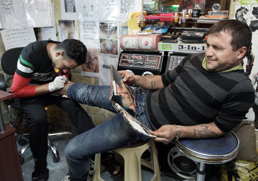 Saad Saif, 25, gets a tattoo done by Mohammed Abass, 28, in Baghdad. He is one of many young Iraqis who have adopted the ways of some of the U.S. soldiers who have been in their country for eight years. For them, rap music, tattoos and American slang are part of what the departing forces are leaving behind. (Associated Press)
