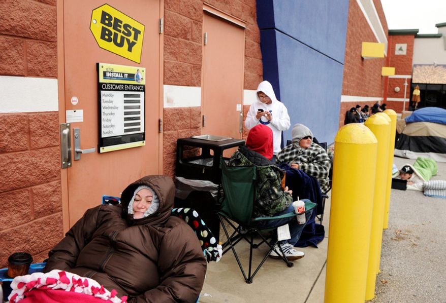 Nicole Bass, left, tries to stay warm while waiting outside of Best Buy in Evansville, Ind., on Thursday, Nov. 24, 2011. Bass got to the store about 11:30 a.m. on Thursday and estimates that she is about 25th in line. She's hoping to get a 42-inch television for $200 when the store opens at midnight. This weekend, many stores will for the first time use midnight openings along with the usual bevy of deals as they try to lure consumers, whose appetite for good-buys has been increasing since the Great Recession. (AP Photo/Evansville Courier & Press, Molly Bartels )
