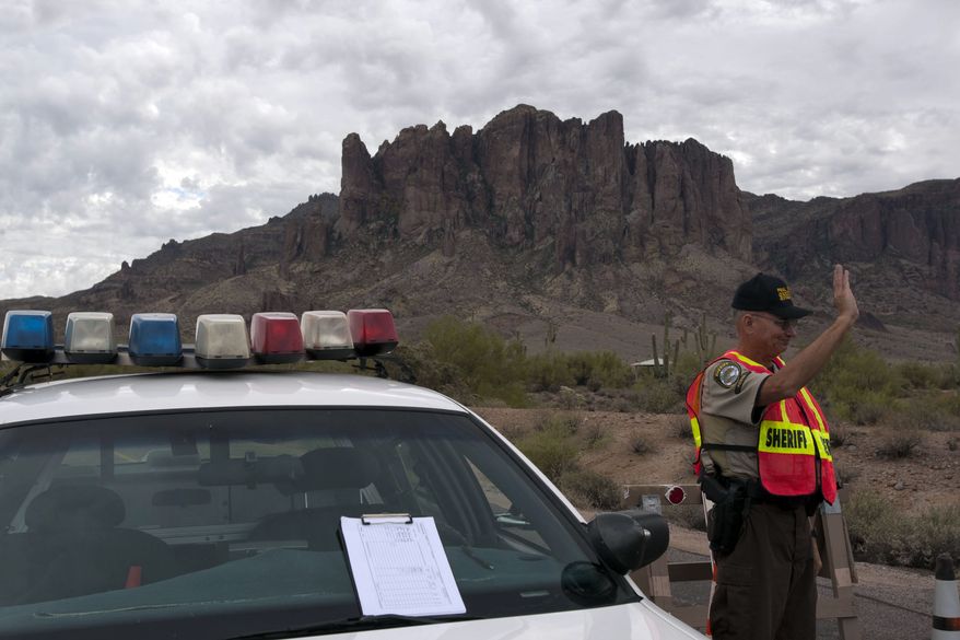 John Kinder, a member of the Posse of Pinal County Sheriff Department, secures a road on Nov. 24, 2011, while a search and rescue team works around the clock at the Superstition Mountains east of Apache Junction, Ariz., where small plane crashed the previous evening. All passengers aboard were killed, including a pilot father and his three children traveling for Thanksgiving. (Associated Press/The Arizona Republic)