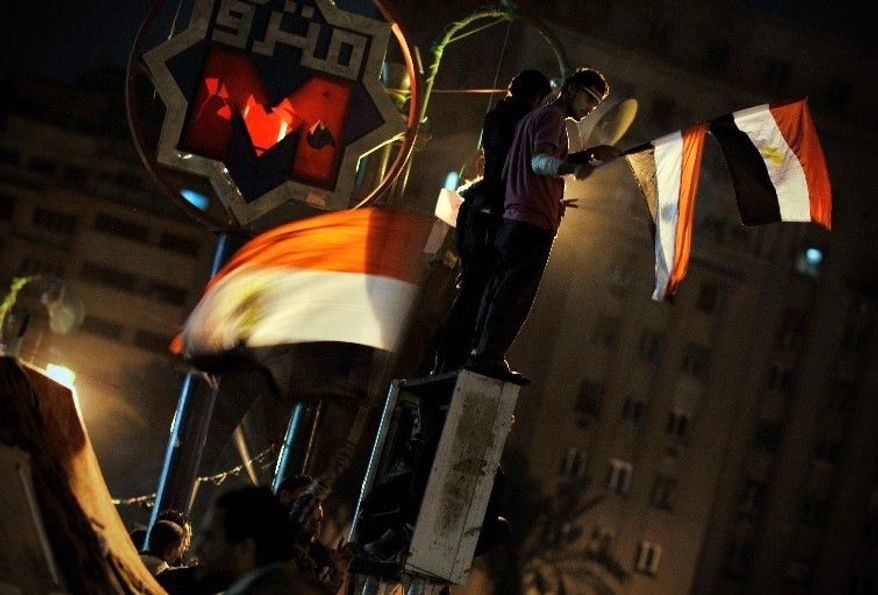 Egyptians wave national flags while protesting against the country's ruling military council in Cairo's Tahrir Square on Sunday. "How can we have elections right after so many people have died?" asked farmer Hemdan El-Ready. (Associated Press)