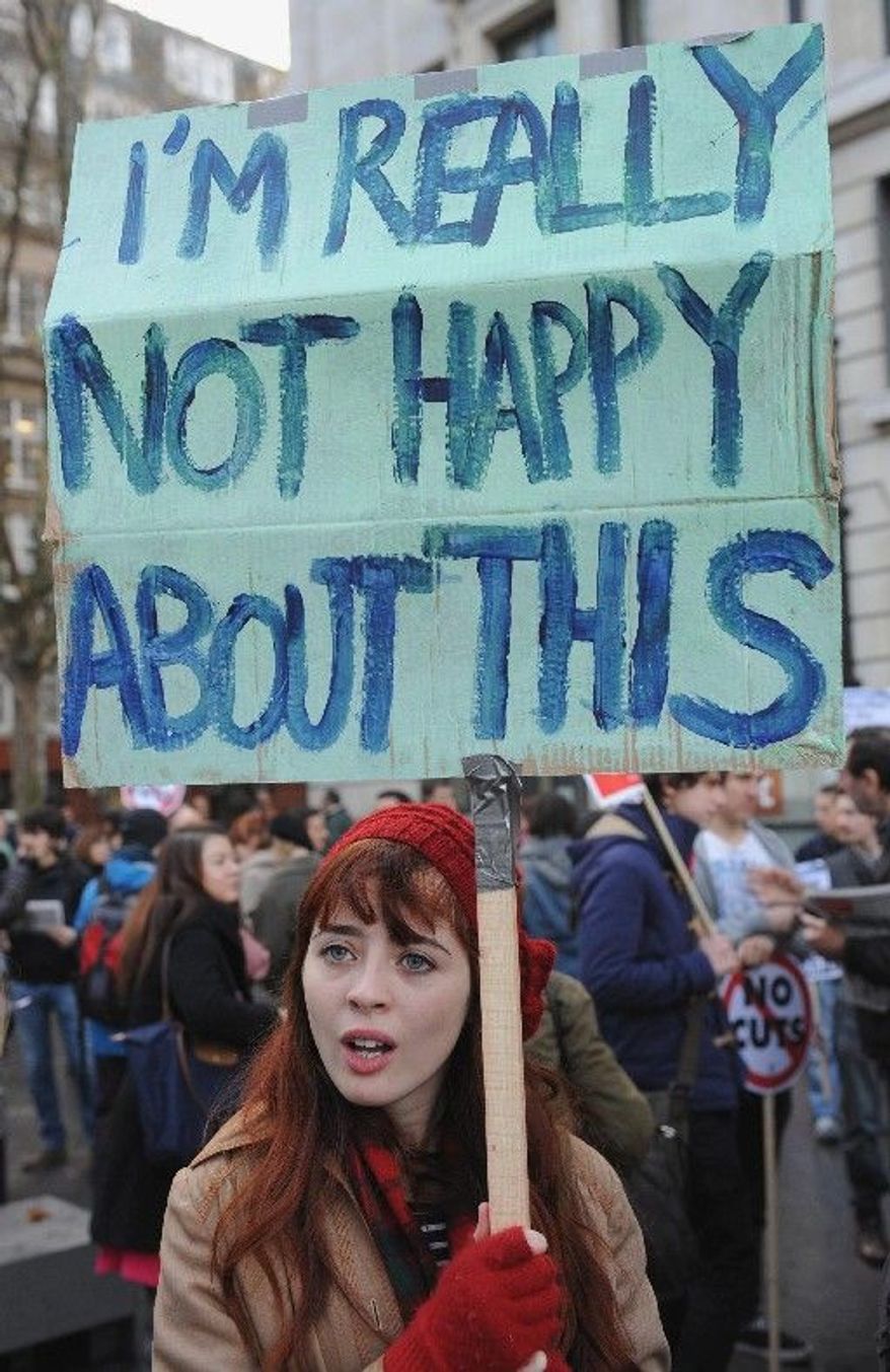 A woman carries a banner Wednesday as public-sector employees march in London during a one-day strike over pensions, the largest such strike in a generation. (Associated Press)