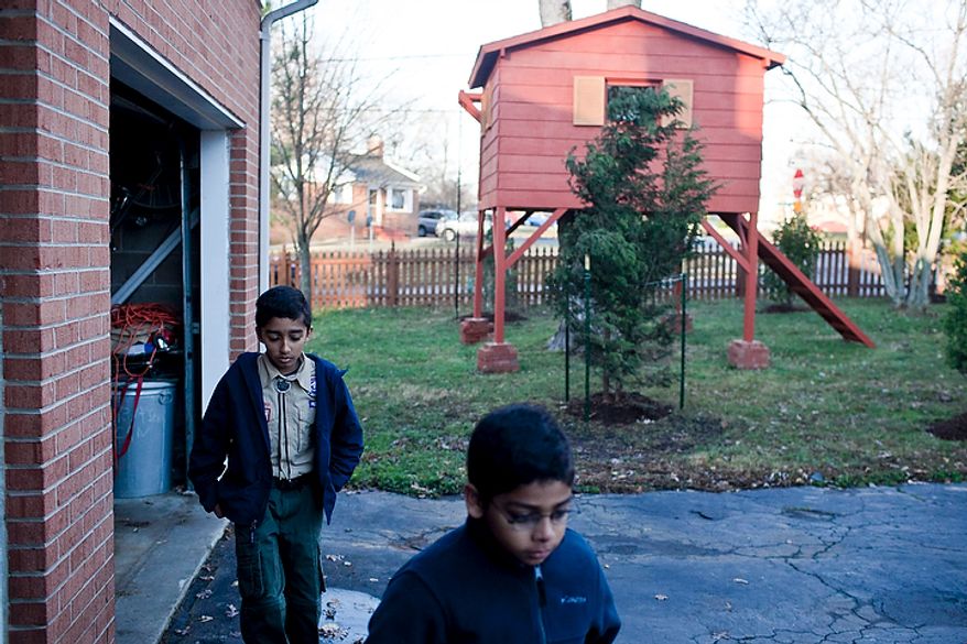 Brothers Eric Grapin, 11, from left, and Sean, 9, walk to the garage past a treehouse in the front yard of his home in Falls Church, Va., on the way to a hearing concerning an ordinance to allow the treehouse to stay in place, on Nov. 30, 2011. (T.J. Kirkpatrick/The Washington Times)