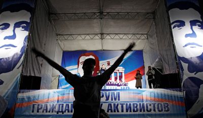 An activist of the Nashi youth movement takes the stage decorated with portraits of Russian President Dmitry Medvedev during a concert in Moscow. Exit polls showed a dramatic drop in support of Prime Minister Vladimir Putin's United Russia party. (Associated Press)