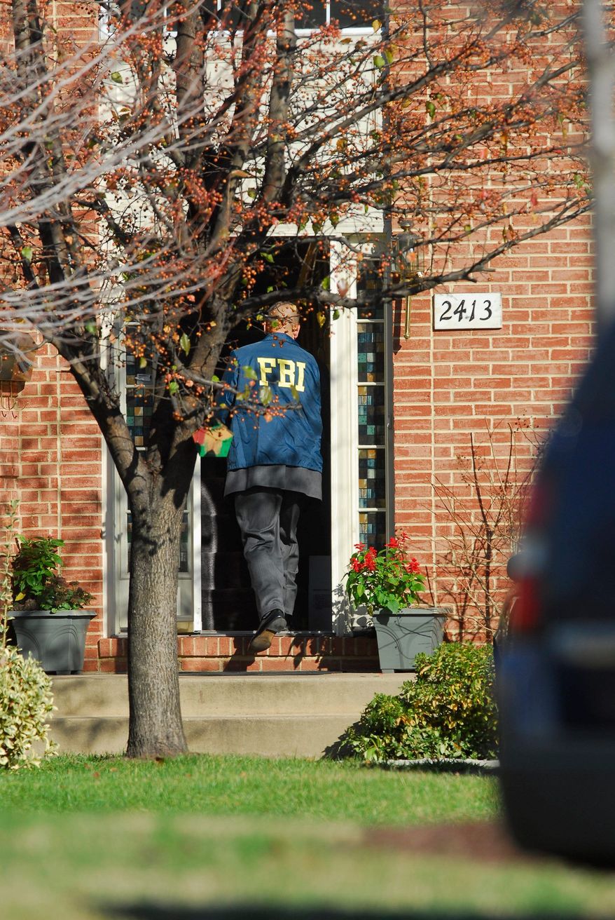 Agents from the FBI and the IRS' Criminal Investigative Division serve a search warrant at the home D.C. Council member Harry Thomas, Jr., on Friday. The agents were at Mr. Thomas' home for more than nine hours and seized a red motorcycle and Chevrolet Tahoe, among other items. (Pratik Shah/The Washington Times)
