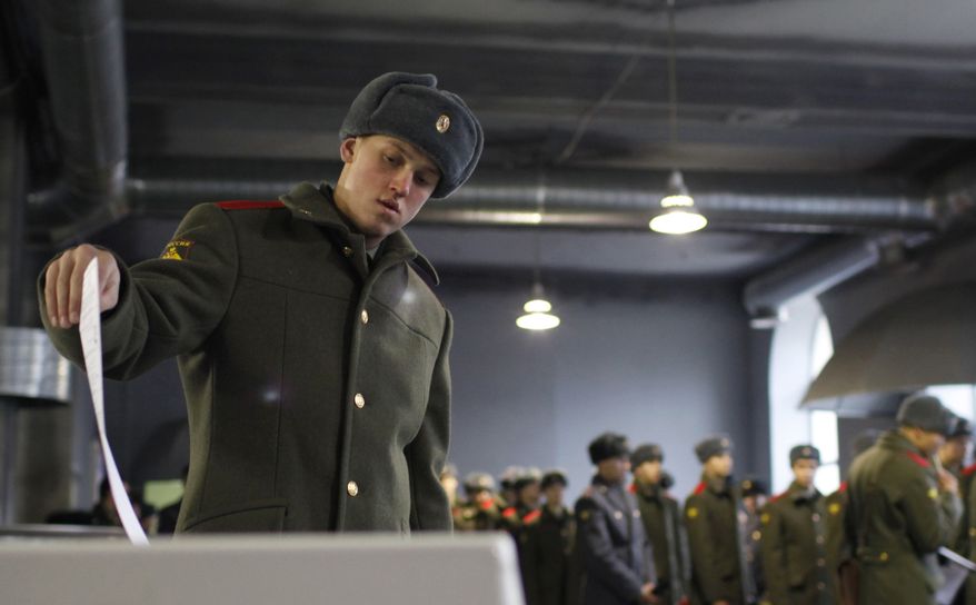 A Russian soldier casts his ballot as others stand in line at a polling station in Moscow on Sunday, Dec. 4, 2011. (AP Photo/Alexander Zemlianichenko Jr.)