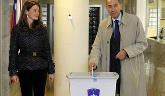 Opposition leader Janez Jansa casts his ballot as his wife, Urska Bacovnik, looks on at a polling station in Velenje, Slovenia, on Sunday, Dec. 4, 2011. (AP Photo)