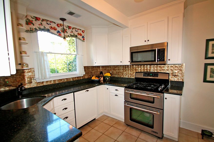 The renovated kitchen has granite counters, stainless steel appliances, gas cooking and a pressed-tin backsplash.