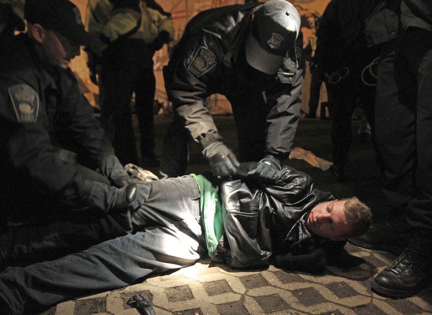 Boston police officers remove an Occupy Boston protester from Dewey Square in Boston before dawn Saturday, Dec. 10, 2011. More than 40 people were peacefully arrested as the park was cleared. The city had set a Thursday midnight deadline for protesters to leave or face eviction. (AP Photo/The Boston Globe, Essdras M Suarez, , Pool)