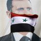 A Syrian flag flies in front of a large banner of President Bashar Assad as demonstrators rally in support of the Assad regime in Damascus, Syria, on Friday, Dec. 9, 2011. (AP Photo/Muzaffar Salman)