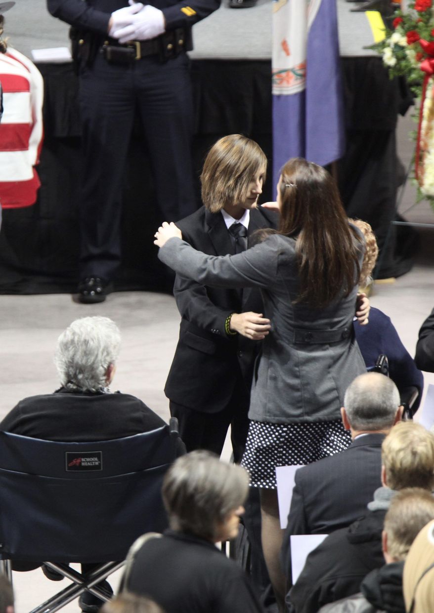 The family of Officer Deriek W. Crouse embraces during his memorial service Monday in Blacksburg, Va. (Associated Press)