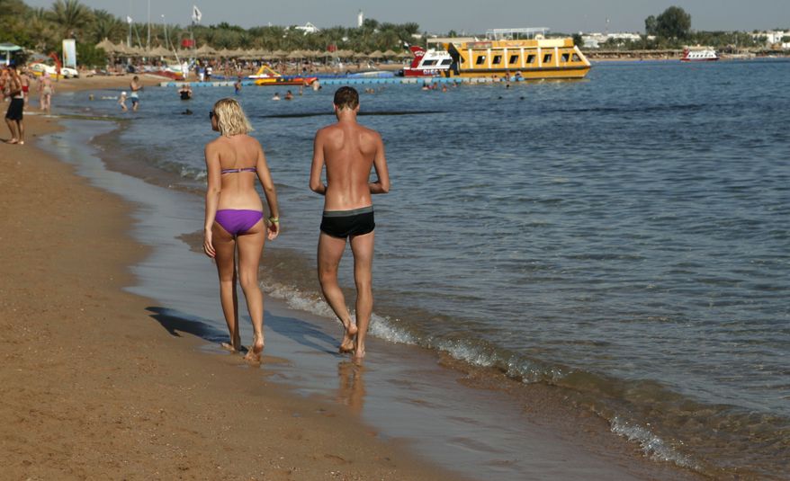 **FILE** A tourist couple walks Dec. 8, 2010, in the shallow waters at a closed beach in the Red Sea resort of Sharm el-Sheik, Egypt. (Associated Press)