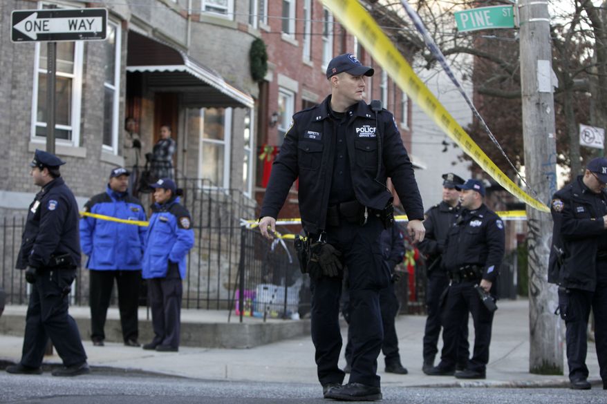 Police officers stand near a crime scene where a fellow officer was shot in the Cypress Hills section of the Brooklyn borough of New York on Monday, Dec. 12, 2011. (AP Photo/Seth Wenig)