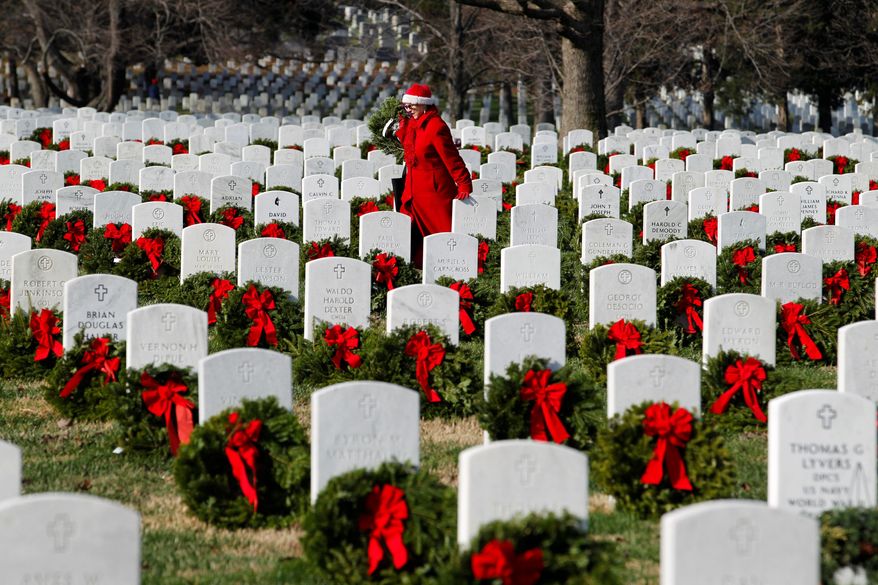Pati Redmond of Frederick, Md., places wreaths last weekend on graves at Arlington National Cemetery, where new leadership has improved operations, two government reports say. (Associated Press)