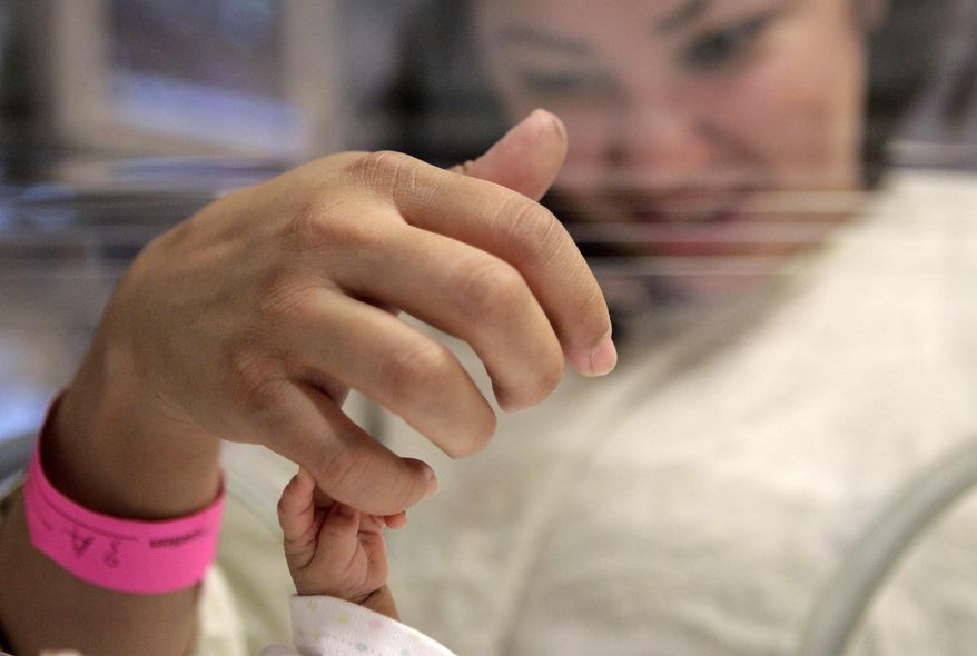 Fourteen-week-old Melinda Star Guido holds her mother's little finger while lying in an incubator at the Los Angeles County-USC Medical Center in Los Angeles, Wednesday, Dec. 14, 2011. (AP Photo/Jae C. Hong)