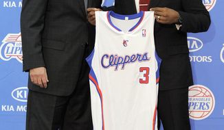 Newly acquired Los Angeles Clippers point guard Chris Paul (right) holds up his jersey Dec. 15, 2011, as he stands with Clippers head coach Vinny Del Negro during a news conference in Los Angeles. (Associated Press)