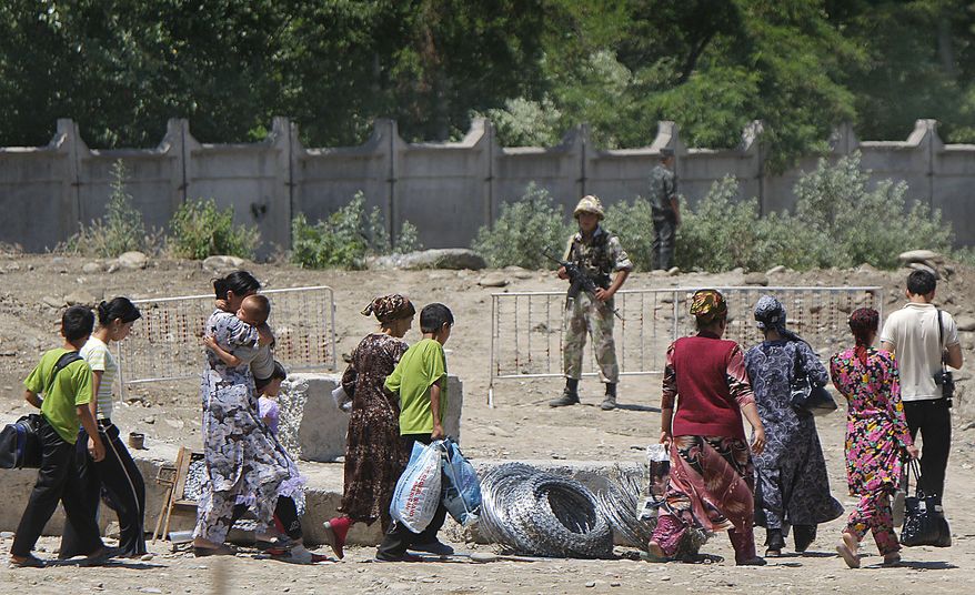 **FILE** Ethnic Uzbeks walk on Uzbekistan territory on June 18, 2010, after crossing the Uzbek-Kyrgyz border near the southern city of Osh as Uzbek border guards look on. (Associated Press)