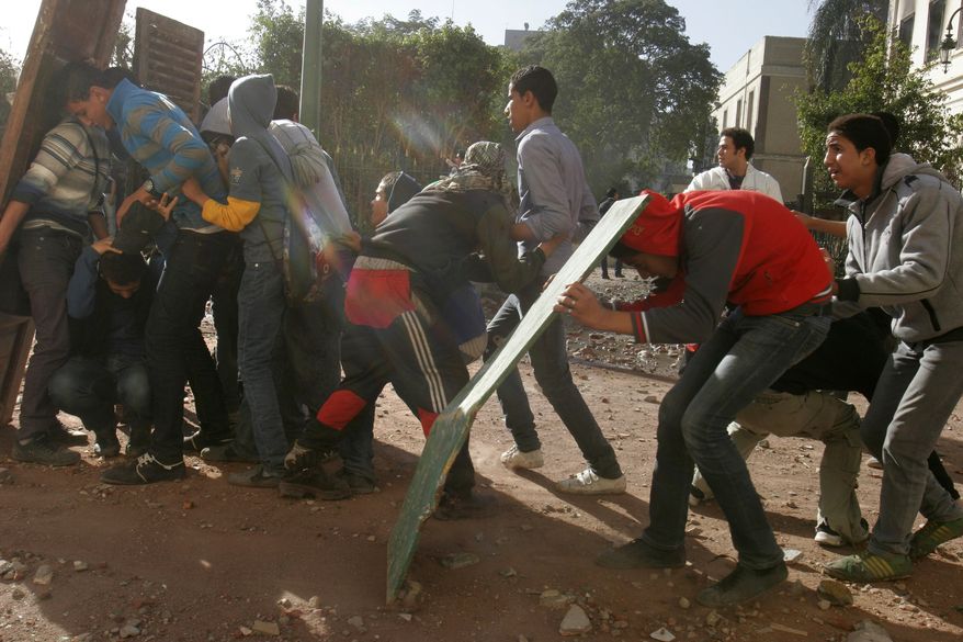 Egyptian protesters protect themselves behind makeshift shields during clashes with army troops near Tahrir Square in Cairo on Sunday, Dec. 18, 2011. (AP Photo/Mohammed Abu Zaid)
