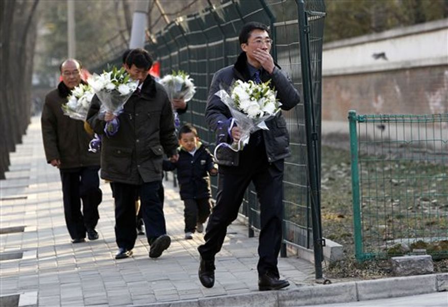 A man reacts as he walks with flowers towards the North Korean Embassy in Beijing on Monday, Dec. 19, 2011. Kim Jong-il, North Korea's mercurial and enigmatic leader, has died, North Korean state media announced Monday. (AP Photo/Ng Han Guan)