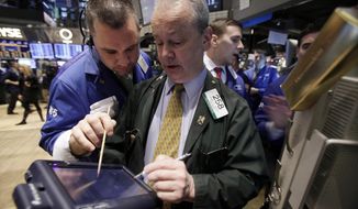 Traders James Lodewick (left) and James Riley (center) work on the floor of the New York Stock Exchange on Tuesday, Dec. 20, 2011. (AP Photo/Richard Drew)