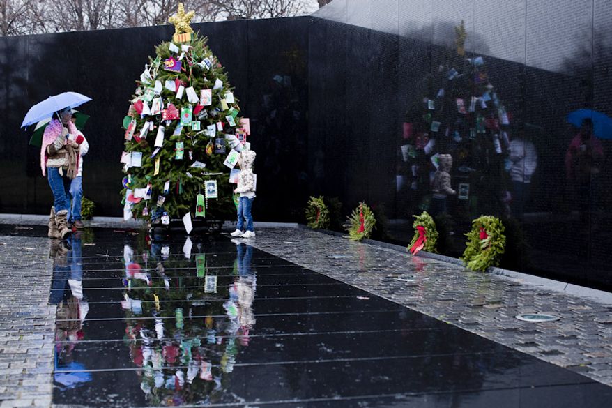 Raene Hicks, of Vale, Ore., from left, with her son Lain, 12, and daughter Sally, 5, look at the Christmas tree in the Vietnam Memorial in Washington, D.C. on Dec. 21, 2011. Raene said both her father and grandfather fought in the Vietnam War aboard the same Navy ship. "Both made it home, my family is blessed," she said, adding that "I come out here to see if I recognize any other names." (T.J. Kirkpatrick/ The Washington Times)